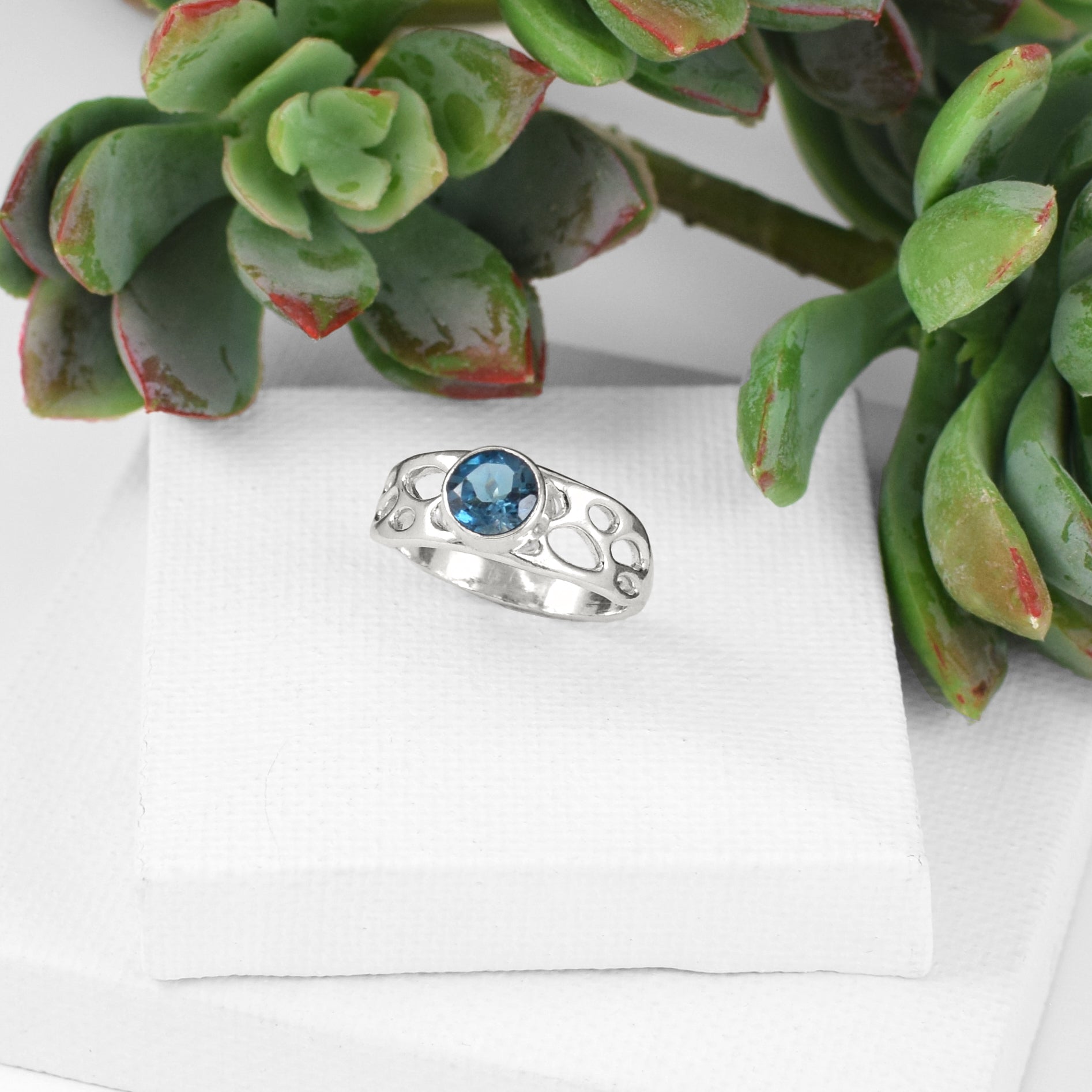 sterling silver botanical solitaire ring with London Blue Topaz on white background