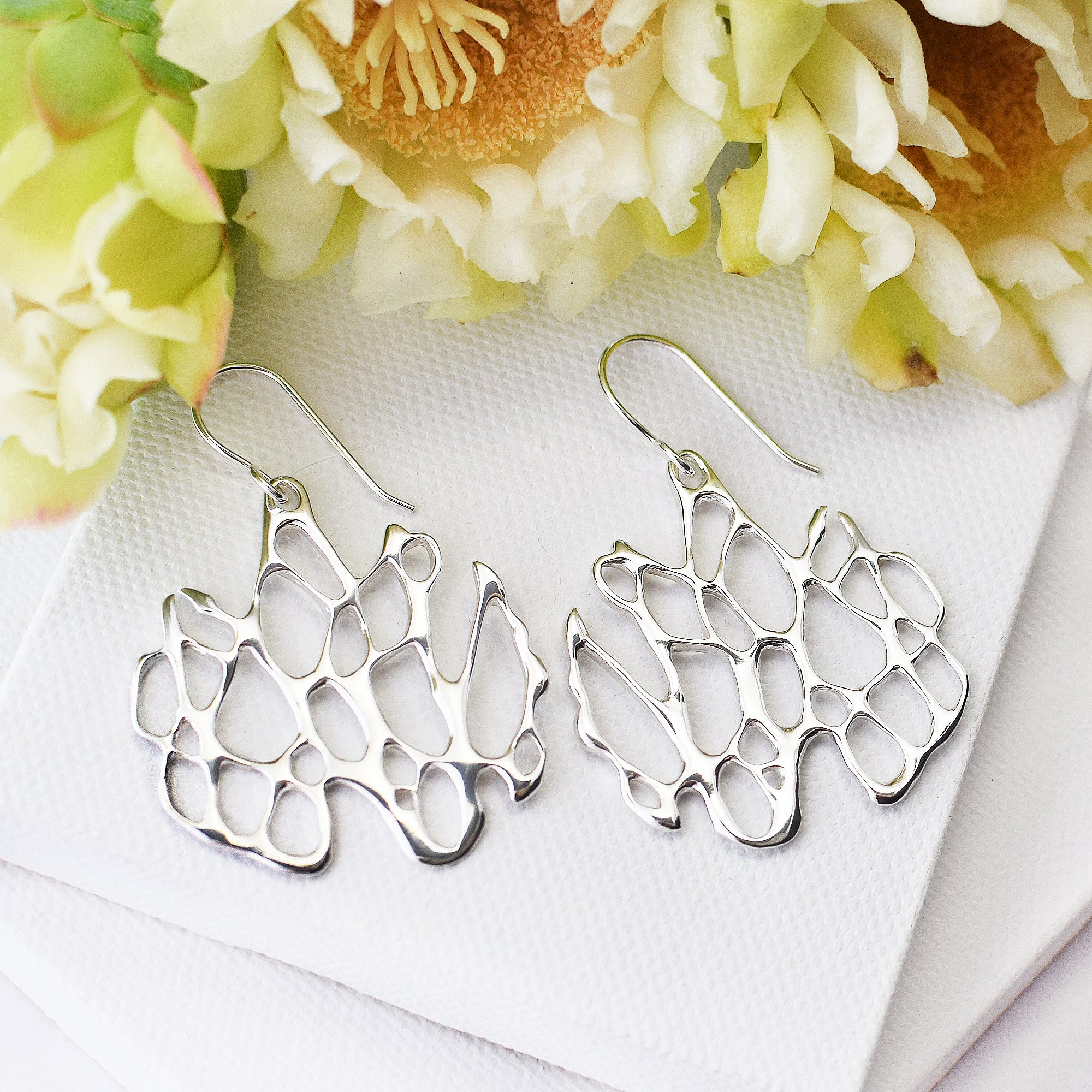 statement silver cactus earrings on white blocks with cactus flower accent