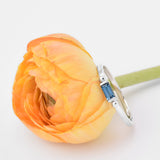 minimalist silver baguette gem ring next to a yellow flower with white background