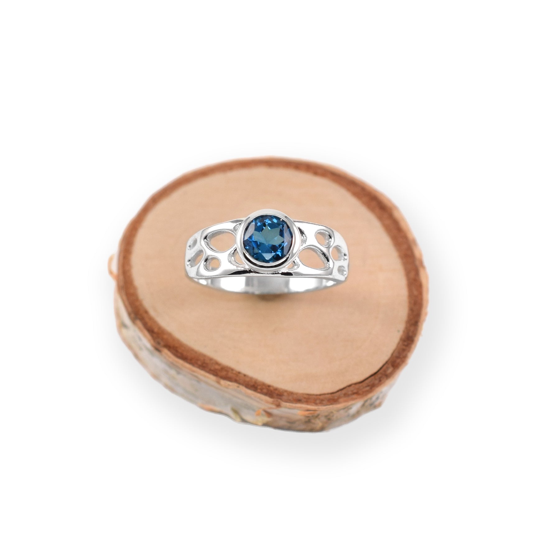botanical solitaire ring with blue gemstone on wood slice