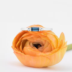 nature inspired silver ring with topaz baguette on top of a yellow flower with white background