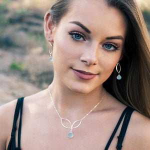 This image is of a woman wearing sterling silver leaf and gemstone jewelry.