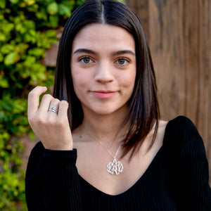 silver botanical ring with gemstone and necklace on woman with plants in background