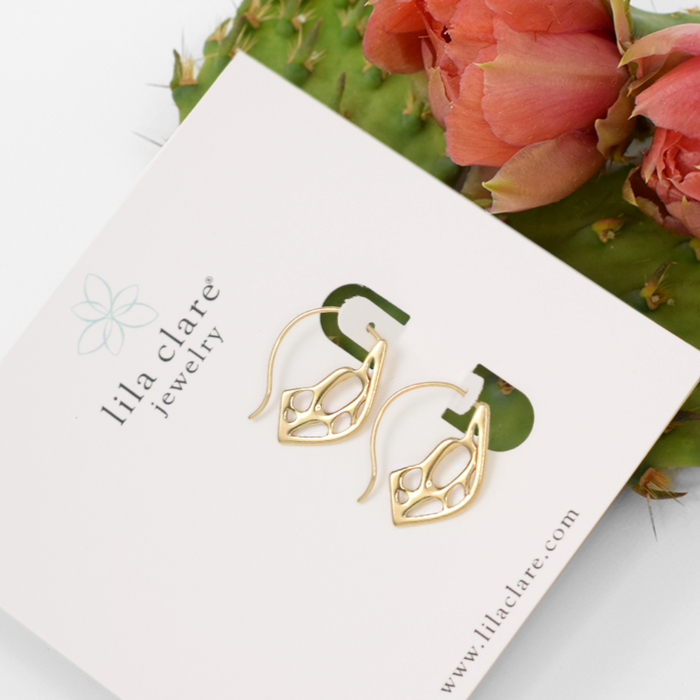 Gold cactus pattern hook earrings on a Lila Clare jewelry card with cactus and flowers in the background